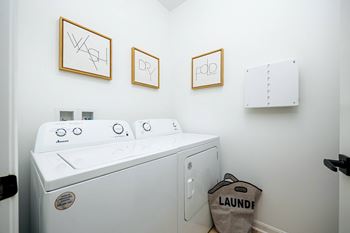 a washer and dryer in a laundry room with three pictures on the wall